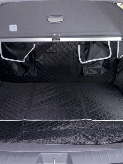 Housse de coffre noire installée dans le coffre d'un SUV, rabats latéraux et poches visibles